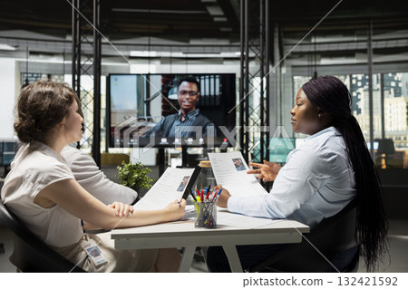Confident candidate joining online video call hiring interview with HR team using high tech office, evaluating the CV and career goals to guarantee potential for the job requirements. Confident candidate joining online video call hiring interview with HR team using high tech office, evaluating the CV and career goals to guarantee potential for the job requirements. 132421592