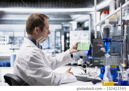 Mockup screen on smartphone used by chemistry expert with laboratory tech at biolab desk, focusing on genetics research, nanotechnology and healthcare data for medical discovery and innovation. 132421593