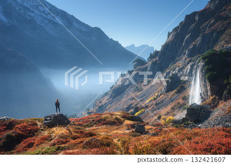 Woman standing on rock near a waterfall in Swiss Alps in autumn 132421607