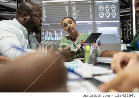 Woman business consultant and staff conducting market trends analysis for goals achievement, reviewing data forecasts in a meeting after hours. Diverse team discussing about progress plans. 132421643