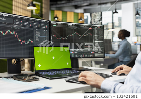 Risk analyst monitors live market activity on isolated screen laptop to identify market volatility signs. Employee reviewing portfolio performance reports on mockup notebook device 132421691
