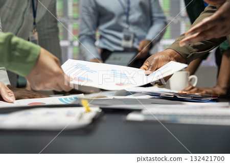 Close up of diverse specialists evaluating data numbers on archived files, exchanging reports and insights to establish clear enterprise objectives in a quiet strategy room late at night. Close up of diverse specialists evaluating data numbers on archived files, exchanging reports and insights to establish clear enterprise objectives in a quiet strategy room late at night. 132421700