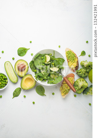 Fresh salad bowl, avocado toasts, raw green vegetables fruit white background top view, diet, vegetarian healthy food Fresh salad bowl, avocado toasts, raw green vegetables fruit white background top view, diet, vegetarian healthy food 132421991
