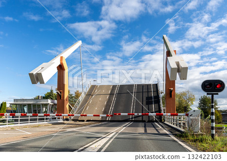 Modern drawbridge stands open bright blue sky with red traffic lights safety barriers in Netherlands. Dutch engineering structure connects roads canal, showing motion urban infrastructure Modern drawbridge stands open bright blue sky with red traffic lights safety barriers in Netherlands. Dutch engineering structure connects roads canal, showing motion urban infrastructure 132422103
