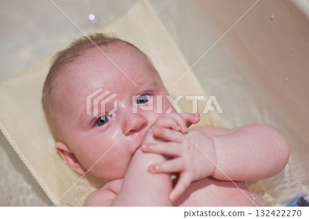 Infant baby boy washed in small bath tub, view from above 132422270