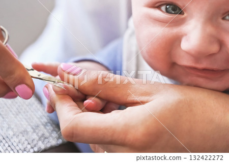 Infant baby boy having his nails cut by mother, detail on scissors and fingertips Infant baby boy having his nails cut by mother, detail on scissors and fingertips 132422272