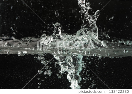 Water splashing as it's poured into aquarium tank, black background 132422280