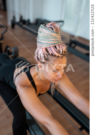 Woman training pilates on the reformer bed. Reformer pilates studio machine for fitness workouts in gym. Fit, healthy and strong authentical body. Fitness concept Woman training pilates on the reformer bed. Reformer pilates studio machine for fitness workouts in gym. Fit, healthy and strong authentical body. Fitness concept 132422528