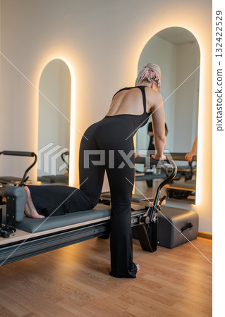 Pilates, reformer and women in class with machine for exercise, workout and improve posture. Fitness club, trainer and people with resistance equipment for wellness, health and balance for strength Pilates, reformer and women in class with machine for exercise, workout and improve posture. Fitness club, trainer and people with resistance equipment for wellness, health and balance for strength 132422529