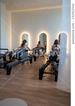 Studio reformer class dynamics, energetic group pilates reformer session with focused movement Studio reformer class dynamics, energetic group pilates reformer session with focused movement 132422542