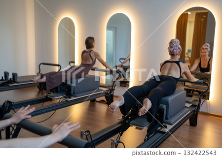 Studio reformer class dynamics, energetic group pilates reformer session with focused movement Studio reformer class dynamics, energetic group pilates reformer session with focused movement 132422543