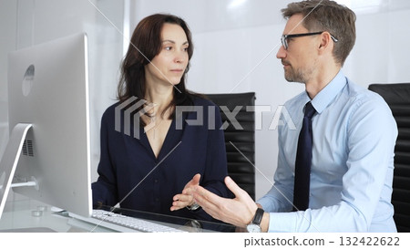 Businessman and business woman colleagues collaborating on computing project in office, discussing data, sharing ideas, and developing solutions, fostering teamwork and professional partnership 132422622