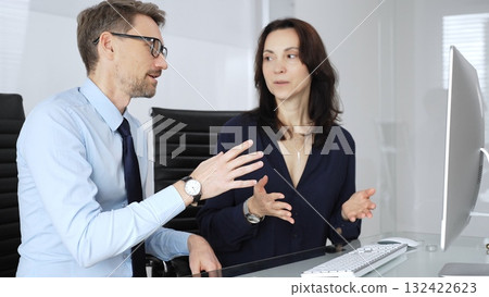 Business professional colleagues or partners collaborating and communicating on a desktop computer, analyzing information, sharing insights, and developing strategies in a modern office environment 132422623