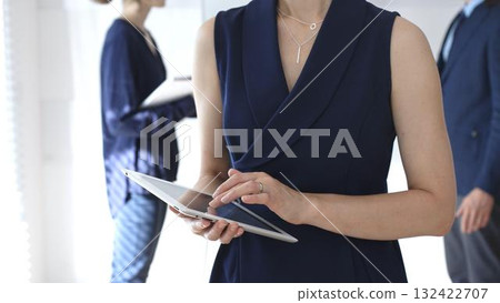 Businesswoman using digital tablet during corporate meeting, collaborating with colleagues in a modern office, planning strategies for project development and success 132422707