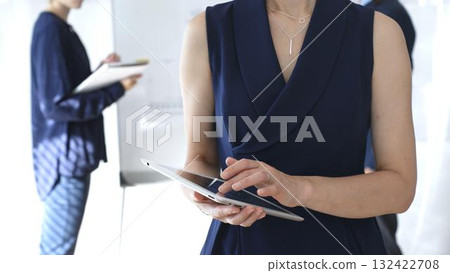Businesswoman using digital tablet during corporate meeting, collaborating with colleagues in a modern office, planning strategies for project development and success 132422708