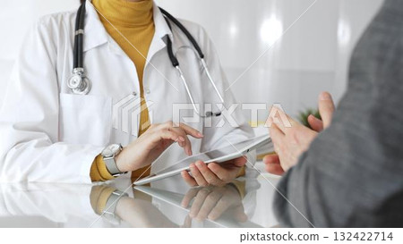 Doctor consulting patient using digital tablet, explaining medical information during modern healthcare appointment. Medicine, healthcare and science concept 132422714