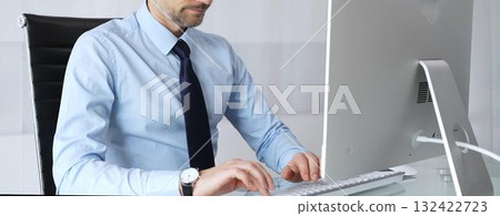 Mature businessman in office concentrating on important computer work, typing on keyboard, engaging in professional tasks, representing technology, development, and progress 132422723