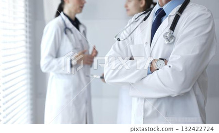 Medical team of doctors collaborating and consulting in a bright hospital setting, showcasing patient care, professionalism, and teamwork among healthcare workers 132422724