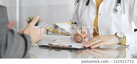 Doctor writing prescription during patient consultation in clinic, providing medical care and diagnosis. Medicine, healthcare and science concept Doctor writing prescription during patient consultation in clinic, providing medical care and diagnosis. Medicine, healthcare and science concept 132422733