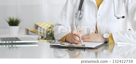 Female physician or medic completing paperwork, preparing a diagnosis, or providing healthcare service in a clean modern office. Medicine, healthcare and science concept Female physician or medic completing paperwork, preparing a diagnosis, or providing healthcare service in a clean modern office. Medicine, healthcare and science concept 132422739
