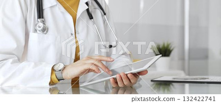Doctor using tablet, working in clinic office, health care professional analyzing electronic medical records data. Medicine, healthcare and science concept Doctor using tablet, working in clinic office, health care professional analyzing electronic medical records data. Medicine, healthcare and science concept 132422741