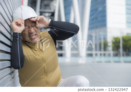 A man in work clothes with an air-conditioned vest suffering from heatstroke A man in work clothes with an air-conditioned vest suffering from heatstroke 132422947