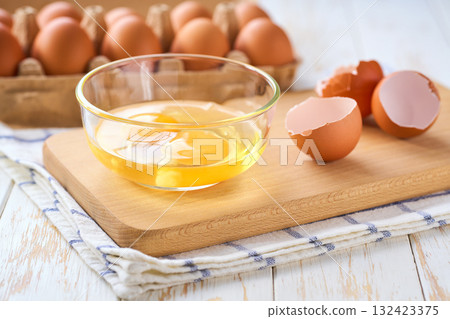 Cracked raw eggs on a light-colored kitchen table, selective focus. Cracked raw eggs on a light-colored kitchen table, selective focus. 132423375