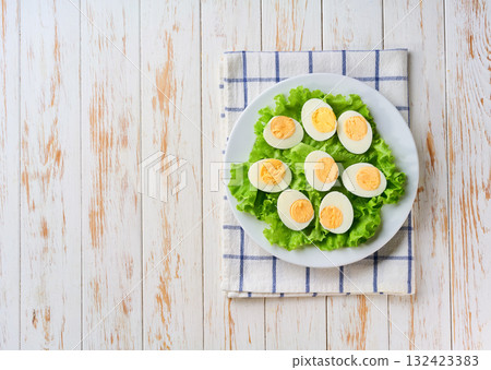 hard-boiled eggs in a plate on a light kitchen table, top view. hard-boiled eggs in a plate on a light kitchen table, top view. 132423383