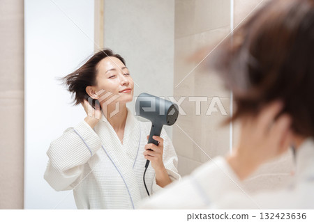 A woman using a hair dryer after taking a bath 132423636