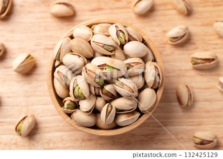 Roasted Pistachio nuts in a bowl on wooden background, Table top view Roasted Pistachio nuts in a bowl on wooden background, Table top view 132425129