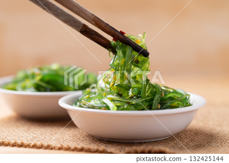 Wakame seaweed salad with sesame seed in a bowl with chopsticks 132425144