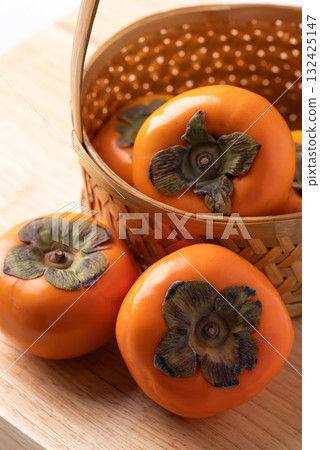 Ripe persimmon fruit in basket on wooden background, Autumn fruit 132425147