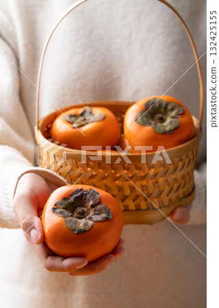 Ripe persimmon fruit in basket holding by hand, Autumn fruit Ripe persimmon fruit in basket holding by hand, Autumn fruit 132425155