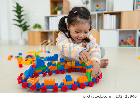 toddler girl playing building blocks or plastic bricks toy at home 132426906