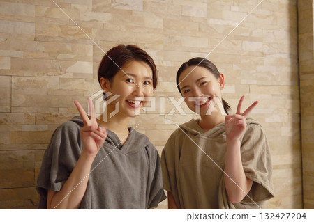 Two women using the sauna making a peace sign 132427204