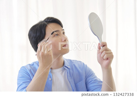 Man in his 20s drawing his eyebrows Man in his 20s drawing his eyebrows 132427338