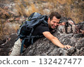 Hiker man climbing natural rocky wall with tropical valley on the background. 132427477