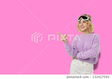 Woman in ski goggles and a purple sweater points confidently 132427593