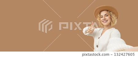 Woman smiling and giving a thumbs up while wearing a sweater Woman smiling and giving a thumbs up while wearing a sweater 132427605