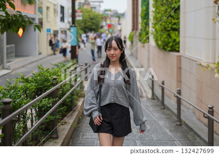 A woman walking down a street in the commercial district of Harajuku A woman walking down a street in the commercial district of Harajuku 132427699