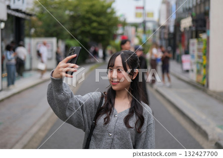 A young woman taking a selfie on the street in the commercial district of Harajuku A young woman taking a selfie on the street in the commercial district of Harajuku 132427700