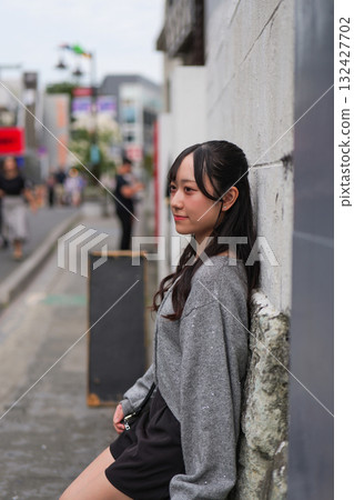 原宿街頭，一位年輕女子靠在牆上的側面照 132427702