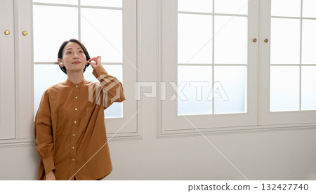 一位女士在窗邊聽音樂或聽收音機 132427740