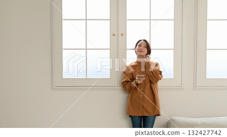 A woman listening to music or the radio by the window 132427742