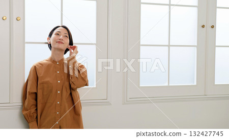 A woman listening to music or the radio by the window A woman listening to music or the radio by the window 132427745