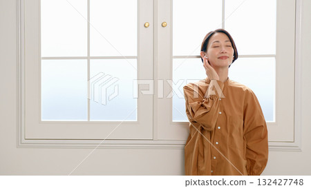 一位女士在窗邊聽音樂或聽收音機 132427748