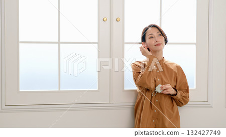 A woman listening to music or the radio by the window A woman listening to music or the radio by the window 132427749