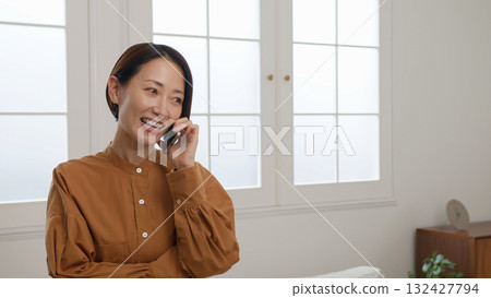 Woman on the phone by the window image 132427794