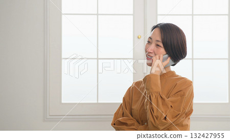 Woman using a phone by the window 132427955