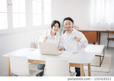 一對夫婦在漂亮的客廳看著鏡頭。這是一幅幸福婚姻的畫面。 一對夫婦在漂亮的客廳看著鏡頭。這是一幅幸福婚姻的畫面。 132428321